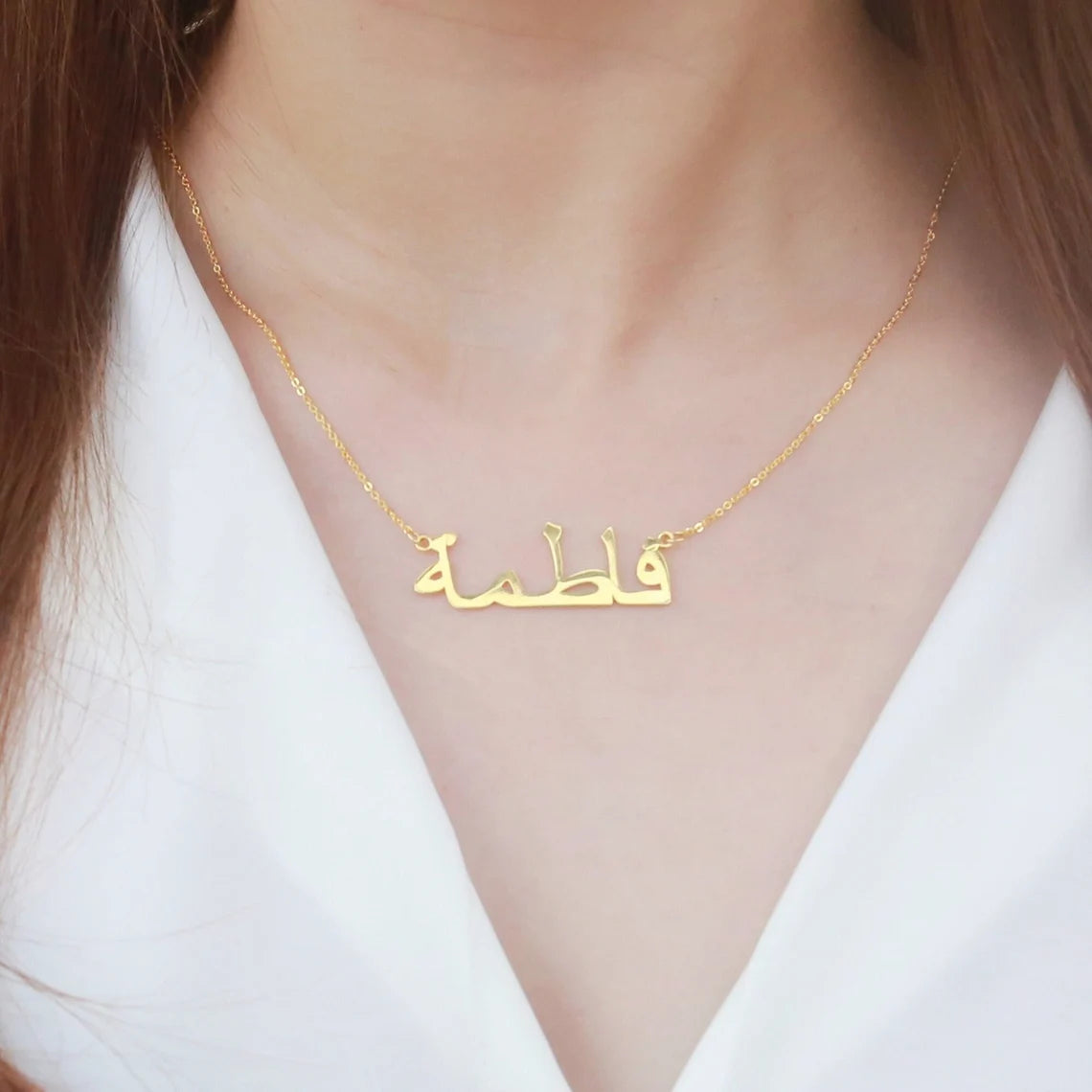 Closeup of a woman wearing a custom Arabic name necklace in gold, highlighting personalized jewelry design for stylish and unique fashion accessories.