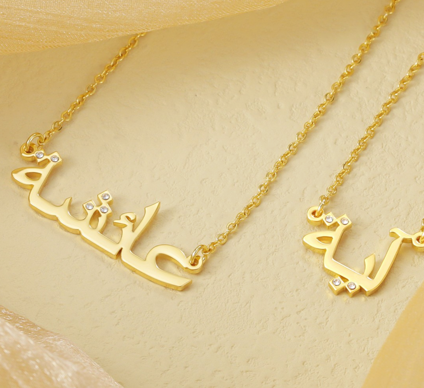 Custom Arabic name necklaces in gold with diamond accents, elegantly displayed on a beige background, showcasing personalized and luxurious jewelry for unique fashion accessories.