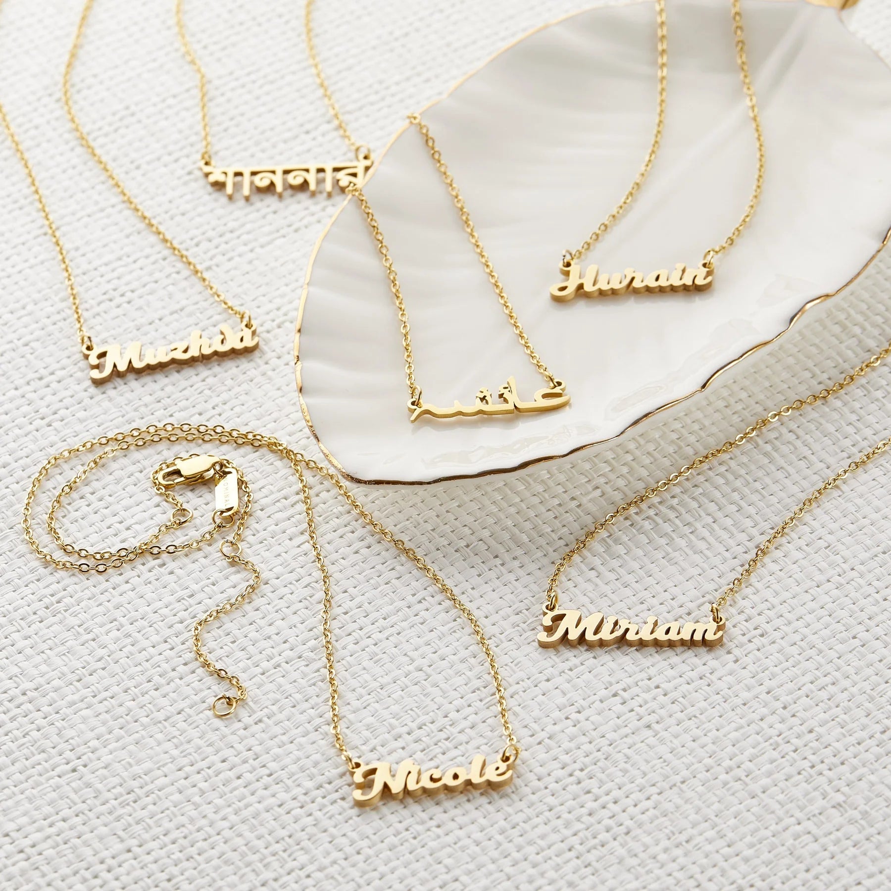 Collection of gold custom name necklaces featuring various names displayed on a white background, showcasing personalized jewelry options for unique fashion accessories.