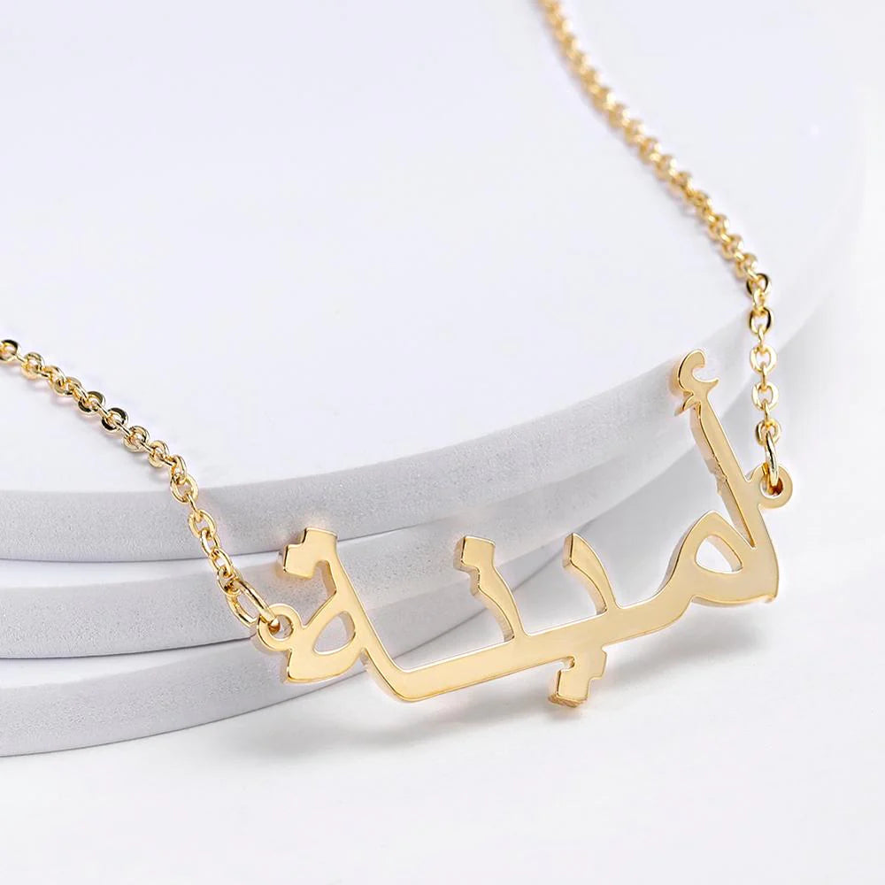 Closeup of a custom Arabic name necklace in gold, elegantly displayed on a white surface, showcasing personalized jewelry design for stylish fashion accessories.