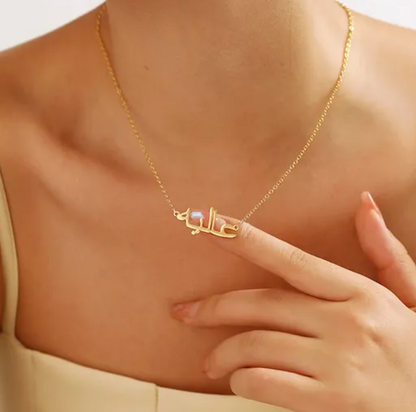  Woman wearing a custom Arabic name necklace in gold, with her finger touching the necklace, highlighting personalized jewelry for unique and stylish fashion accessories.