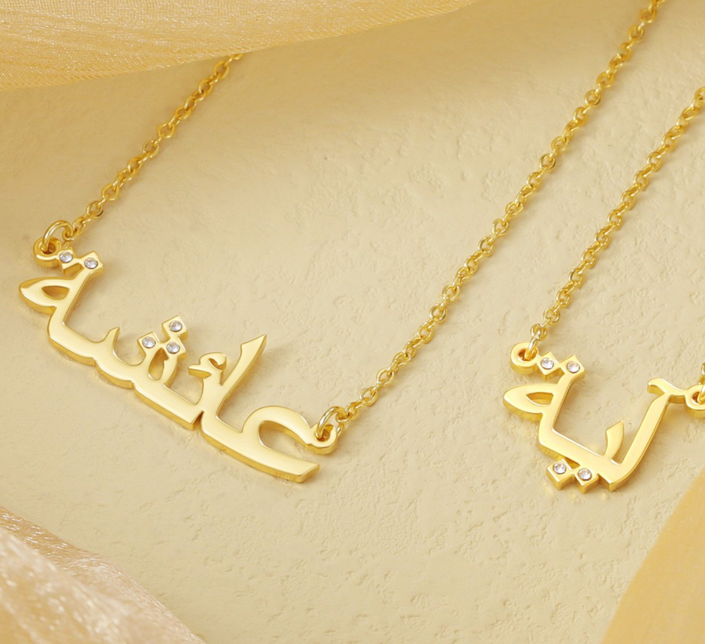  Custom Arabic name necklaces in gold with diamond accents, elegantly displayed on a beige background, showcasing personalized and luxurious jewelry for unique fashion accessories.