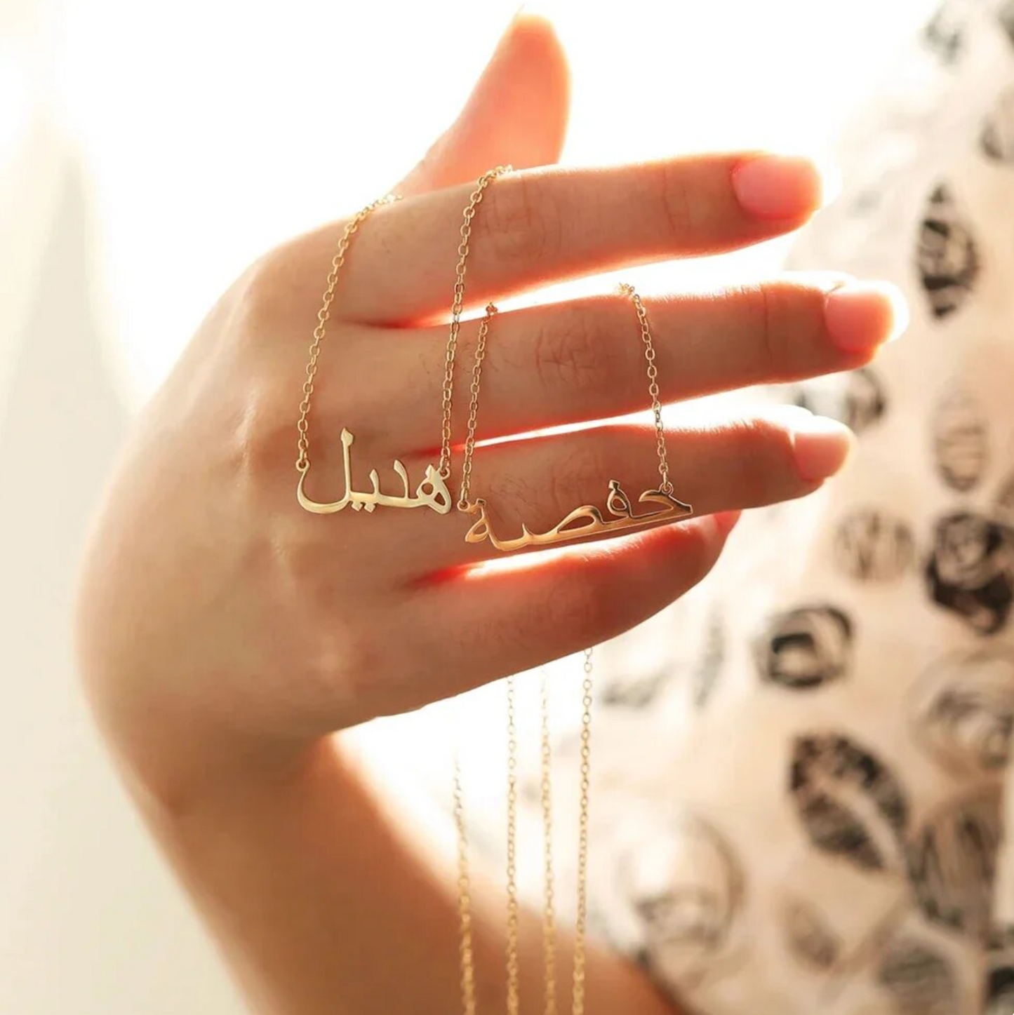 Hand holding multiple custom Arabic name necklaces in gold, highlighting intricate and personalized jewelry designs for unique fashion accessories.