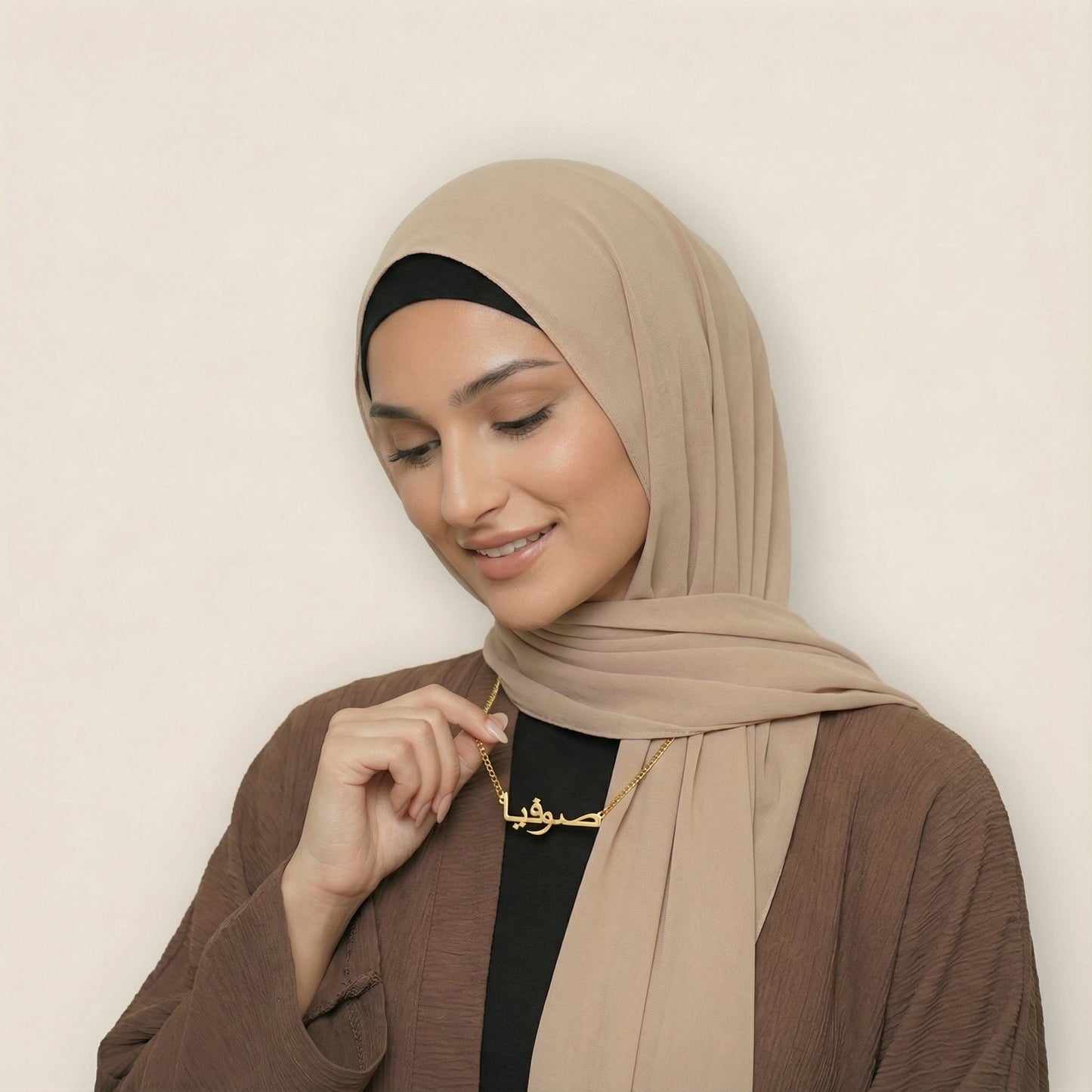 Woman wearing gold custom Arabic name necklace with curb chain looking down