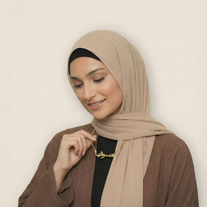 Woman wearing gold custom Arabic name necklace with curb chain looking down