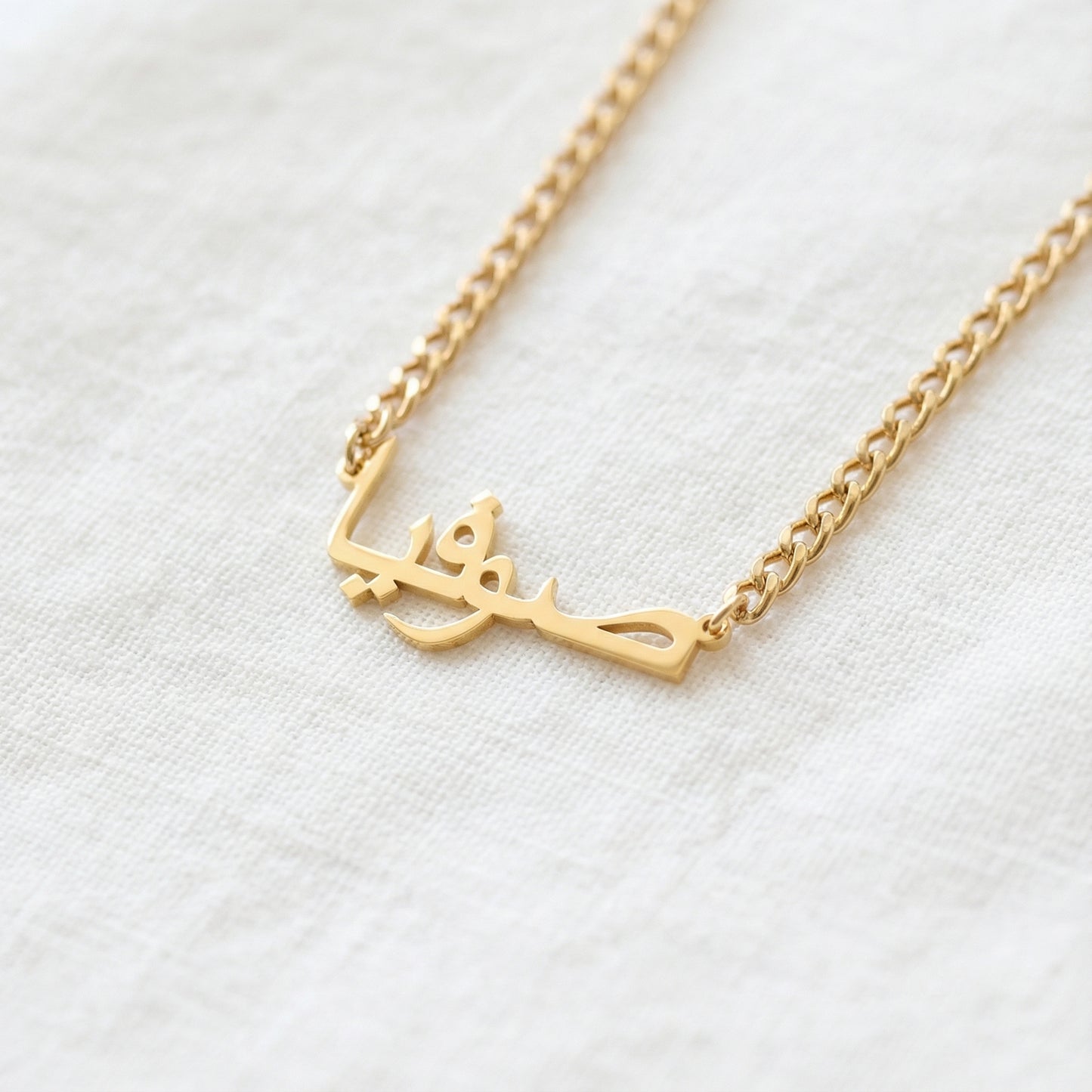 Gold tone custom Arabic script pendant necklace on curb chain close up