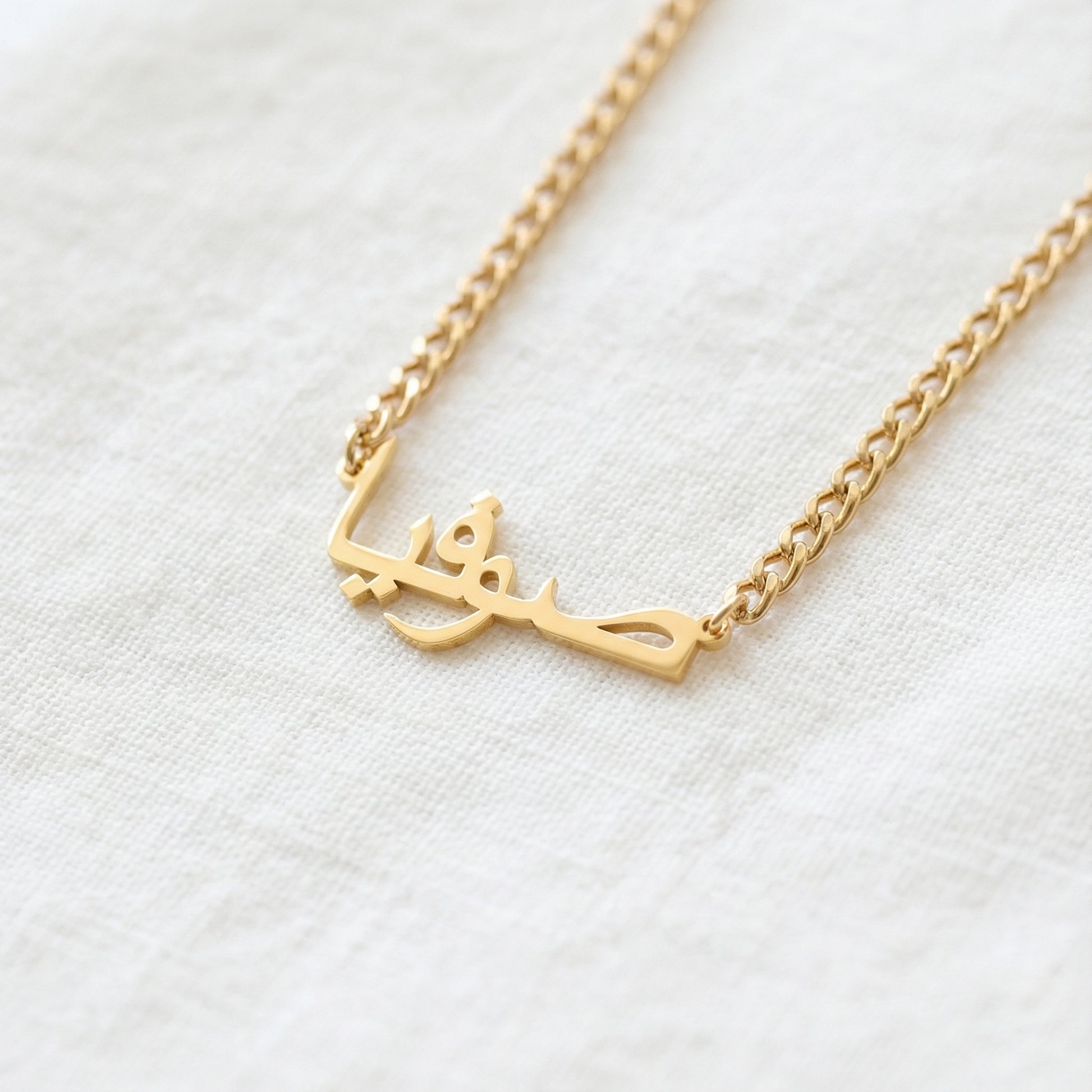 Gold tone custom Arabic script pendant necklace on curb chain close up