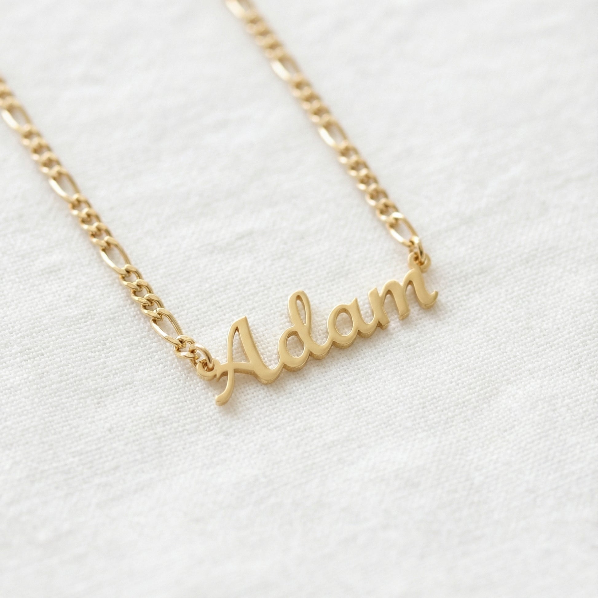 Gold tone English script name necklace reading Adam on 3mm figaro chain