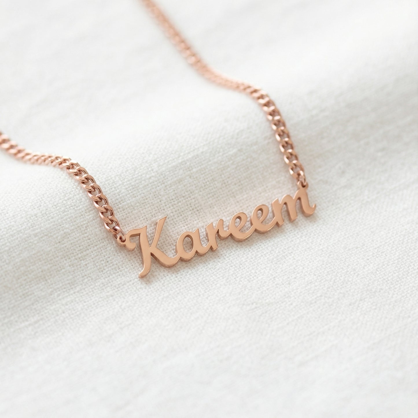 Rose gold tone English script name necklace reading Kareem on curb chain close up