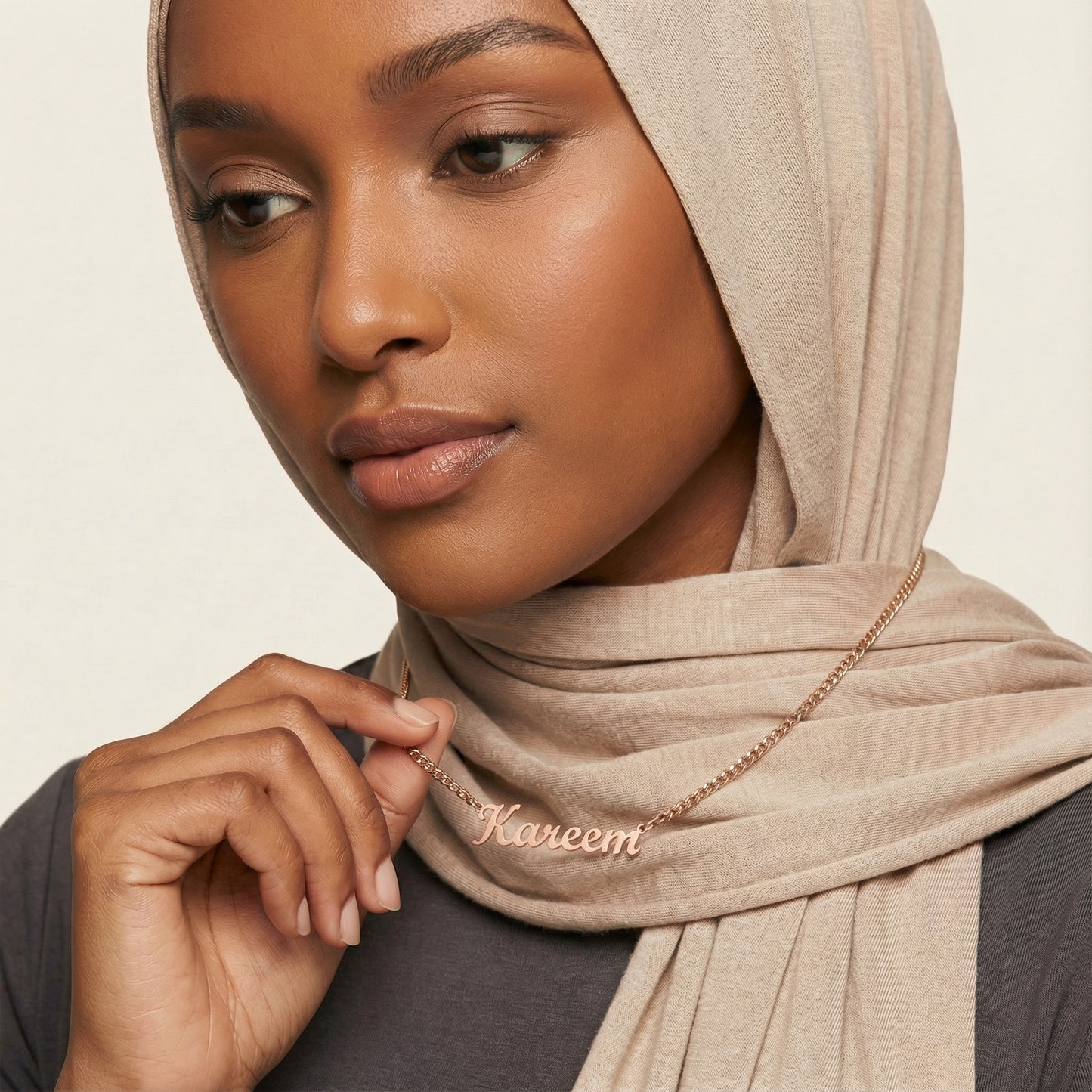 Woman wearing rose gold custom name necklace reading Kareem on curb chain