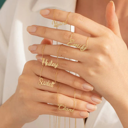 Hand holding multiple custom name necklaces in gold, featuring names like Laura, Emily, Hailey, Scarlett, and Clara, showcasing personalized jewelry for unique fashion accessories.